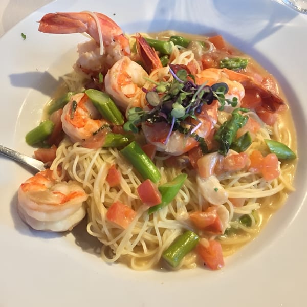 Shrimp scampi with angel hair pasta, asparagus, and diced tomatoes in a white wine sauce.